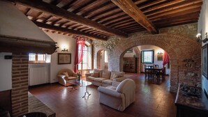 A spacious living room with a high wooden ceiling, a stone archway, and a fireplace. - Green Hill Apt In Tuscan Countryside (Siena)