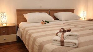 A hotel room with two beds, each with striped bedding and a wooden headboard. There are two bedside tables with lamps, and a small decorative item on one bed. - Old Town Zadar Cozy and Comfy Apartments (Zadar)