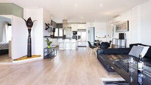 A modern living room with a black sofa, a glass coffee table, and a dining area with a white table and chairs. - Home2Book Chic Penthouse with Terrace, Santa Cruz (Santa Cruz de Tenerife)