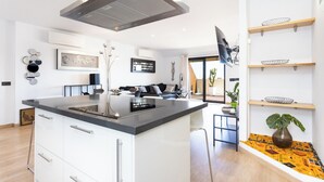 A modern kitchen with a central island, white cabinetry, and a black countertop. - Home2Book Chic Penthouse with Terrace, Santa Cruz (Santa Cruz de Tenerife)