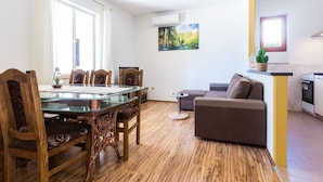 Una sala de estar moderna con una mesa de comedor de vidrio, sillas de madera, un sofá y una pequeña mesa auxiliar.