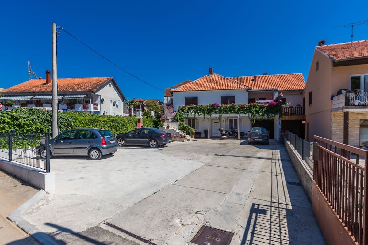 Una calle residencial con casas, coches aparcados y un cielo azul despejado.