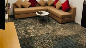 Ein modernes Wohnzimmer mit einem beigefarbenen Ecksofa, einem kleinen runden Couchtisch und einem Flachbildfernseher.
