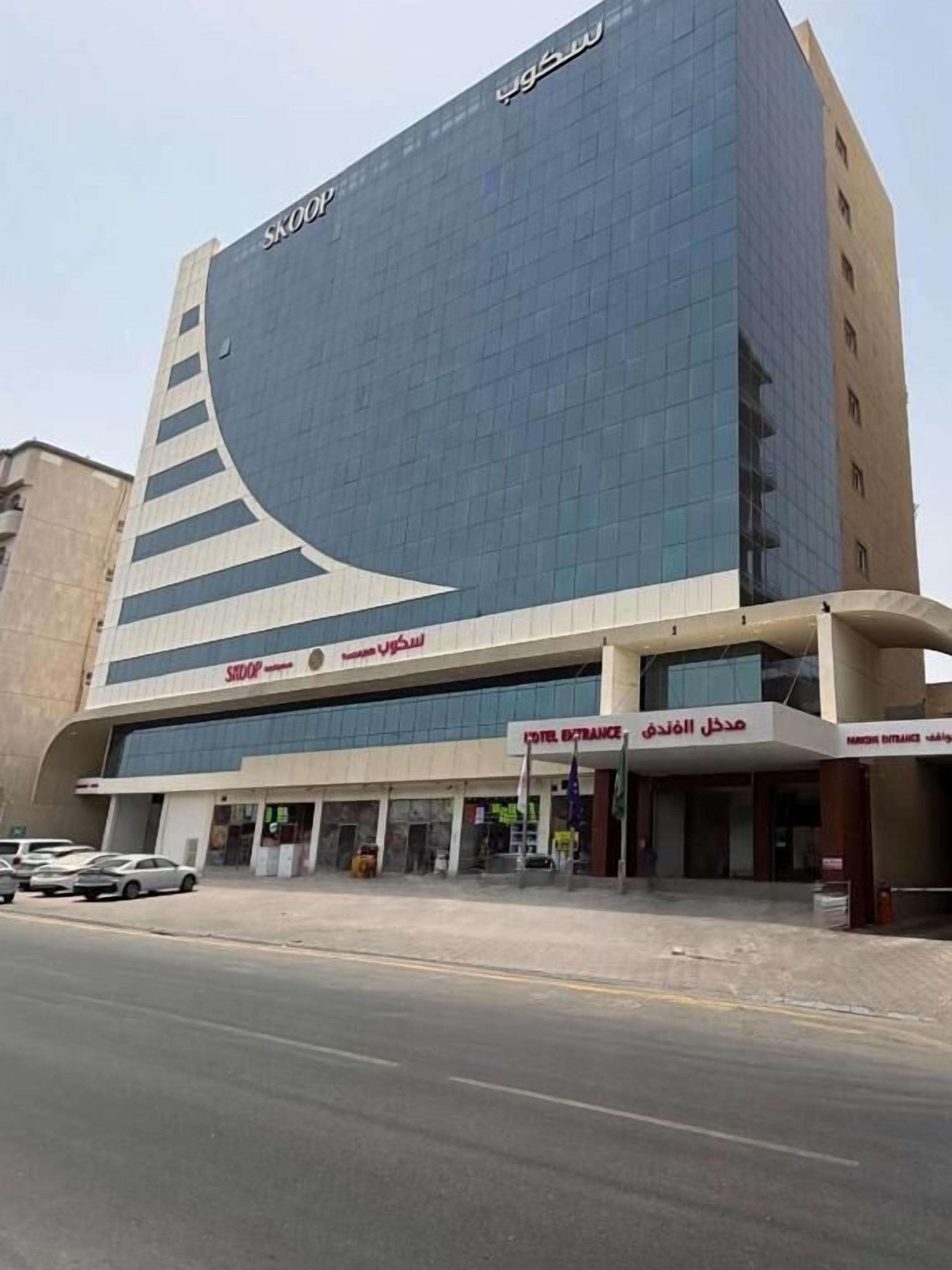 A modern building with a large curved facade, a ground-level entrance, and a visible sign for a hotel.