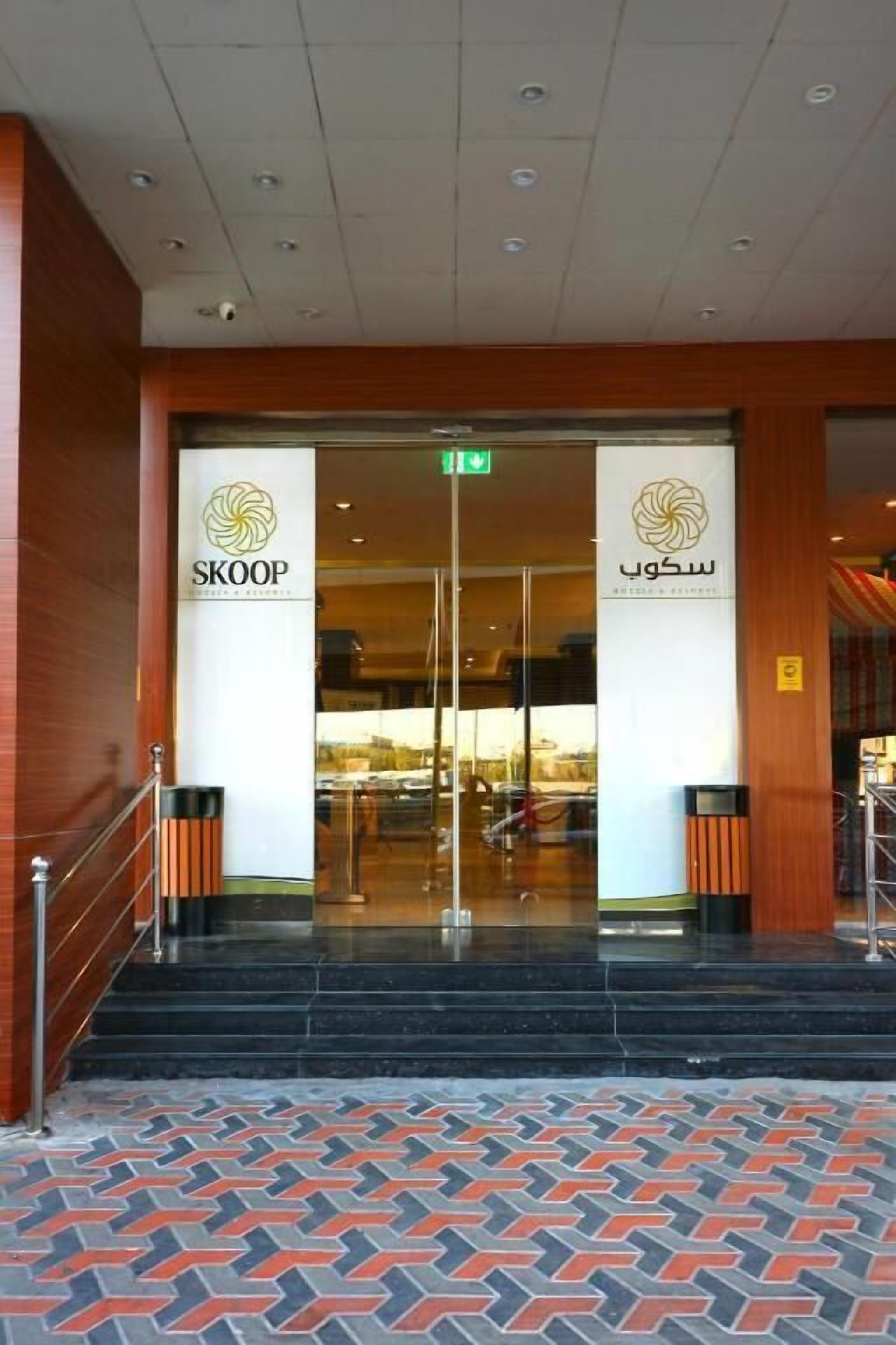 Entrada de hotel con diseño moderno, que presenta un puerta de cristal y un suelo con diseño.