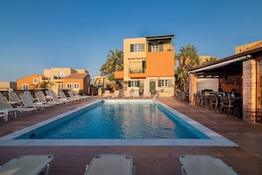Une piscine avec des chaises longues et un bâtiment doté de balcons.