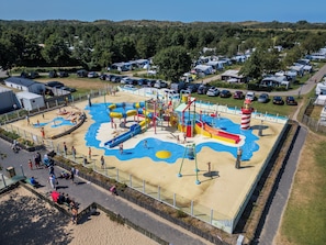 Ein Wasserpark mit Rutschen, einem Wellenbecken und einem Sandspielbereich.