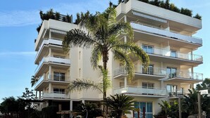 A multi-story hotel with a swimming pool, palm trees, and a sign indicating the pool is closed. - V031 - Port Canigo, V031 - Port Canigo - Apartamento con piscina (Roses)