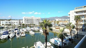 A marina with multiple boats docked, surrounded by buildings and palm trees. - V031 - Port Canigo, V031 - Port Canigo - Apartamento con piscina (Roses)