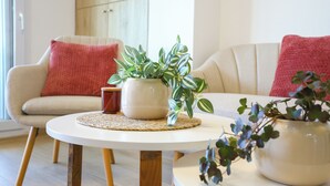 A living room with a round white table, a beige sofa with red cushions, and a potted plant on the table. - V031 - Port Canigo, V031 - Port Canigo - Apartamento con piscina (Roses)