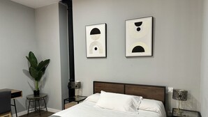 A neatly arranged bedroom with a bed, bedside tables, a lamp, and two framed artworks on the wall. - PlazaMayorSuites Ext PARQUE DEL OESTE (Madrid)