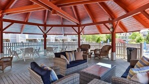 A covered outdoor seating area with wicker furniture and a wooden ceiling. - Oceanfront 3BR condo. 1600 sq ft of extended stay! Weekly and Monthly discounts! (Barnstable)