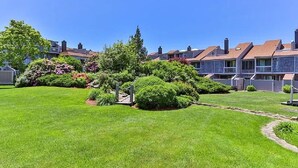 A residential area with well-maintained lawns, a small garden with various plants, and houses with similar architecture. - Oceanfront 3BR condo. 1600 sq ft of extended stay! Weekly and Monthly discounts! (Barnstable)