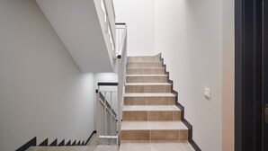 A modern staircase with a straight design, white walls, and a black handrail.