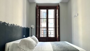 Une chambre à coucher avec un lit, une table de chevet, une lampe et une porte donnant sur l’extérieur.
