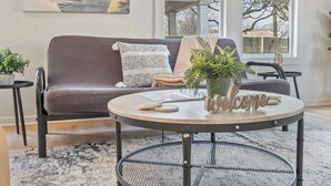 Ein gemütliches Wohnzimmer mit einem runden Metalltisch, einer Couch und einer Topfpflanze.