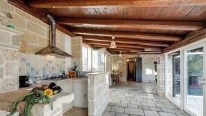 Eine rustikale Küche mit Steinsäulen, Holzbalkendecke und Fliesenrückwand.