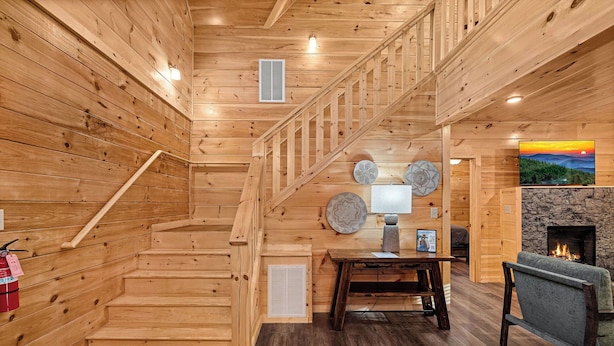 A wooden interior with a staircase, a fireplace, and a dining area. - Welcome to Happy Holler Hideaway (Pigeon Forge)