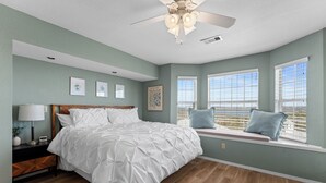 Une chambre à coucher avec un lit, une table de chevet, une lampe et un ventilateur de plafond.