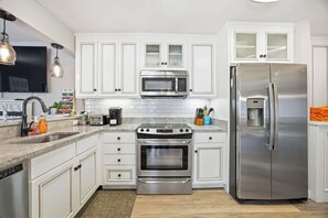A modern kitchen with white cabinetry, stainless steel appliances, a built-in oven, microwave, and refrigerator. - Relaxing Coastal Getaway • 1st-Floor + Pool Access (Hilton Head Island)