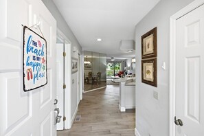A hallway with white doors, a kitchen area with a dining set, and a view of a balcony.