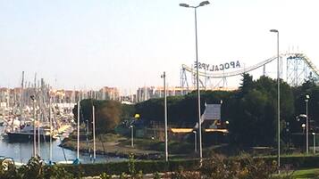 A coastal marina with boats, a roller coaster, and a clear sky.