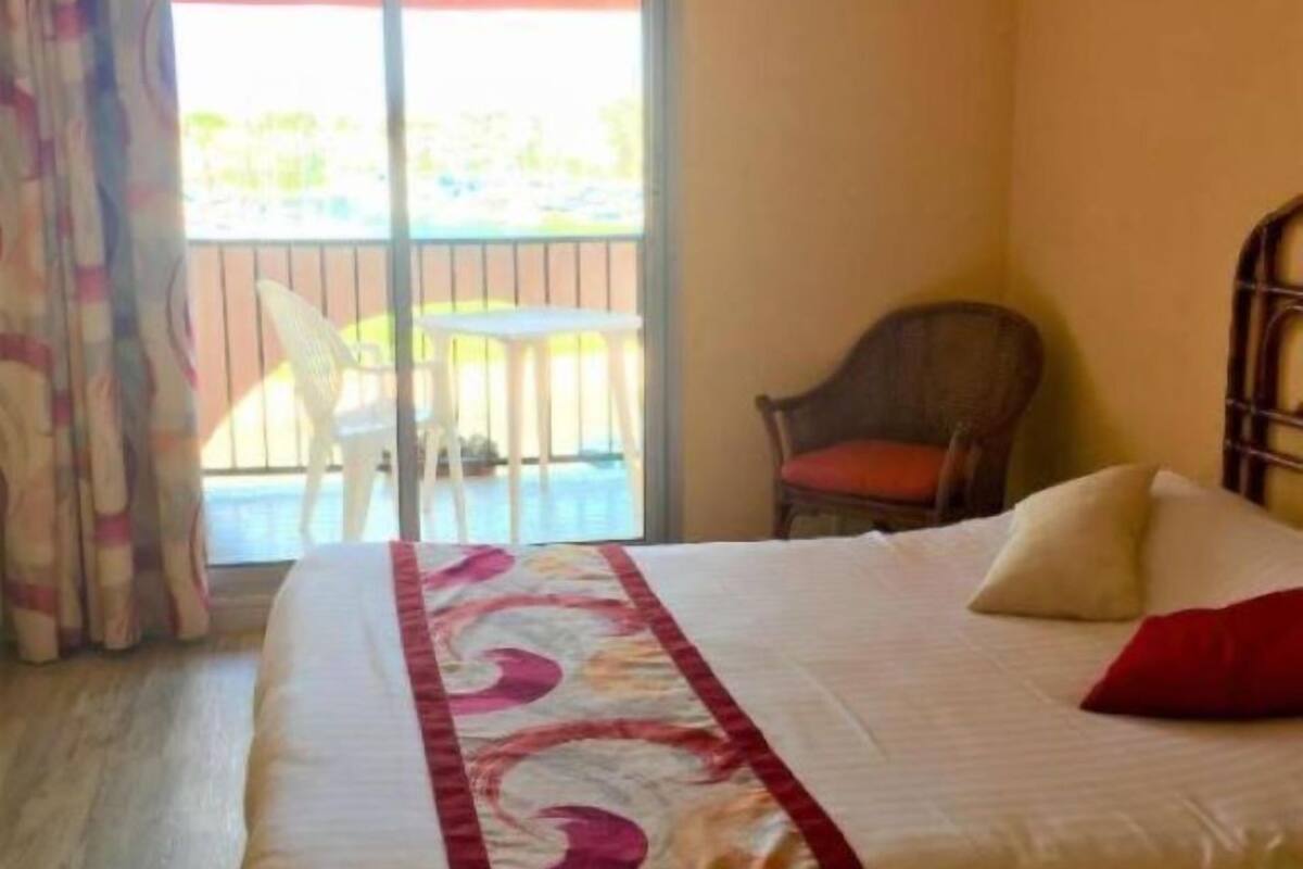 A hotel room with a bed, a chair, and a balcony.