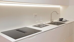 Una cocina moderna con una encimera elegante, un lavamanos integrado y una campana extractora empotrada.