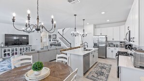 Una cocina moderna con armarios blancos, electrodomésticos de acero inoxidable y una isla central.