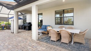 Un patio exterior con una mesa de comedor y sillas, una parrilla y un sofá azul.
