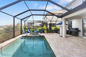Un espace extérieur avec une piscine, des chaises bleues et un barbecue.