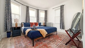 A bedroom with a bed, nightstands, a mirror, and patterned curtains. - Near NYC & Transit ~ Family Friendly ~ Whole House (New Rochelle)