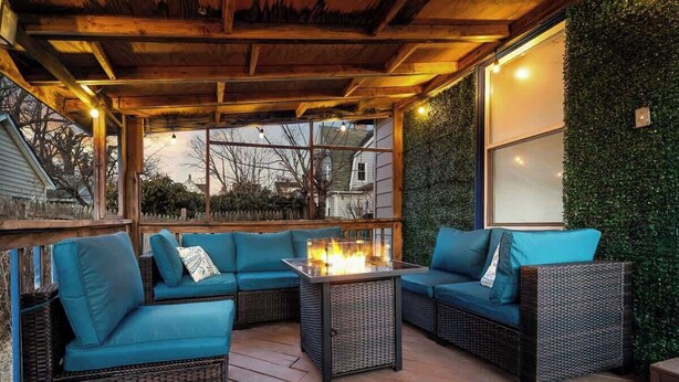 A covered outdoor seating area with wicker furniture and a glass-top table with a fire feature. - Near NYC & Transit ~ Family Friendly ~ Whole House (New Rochelle)