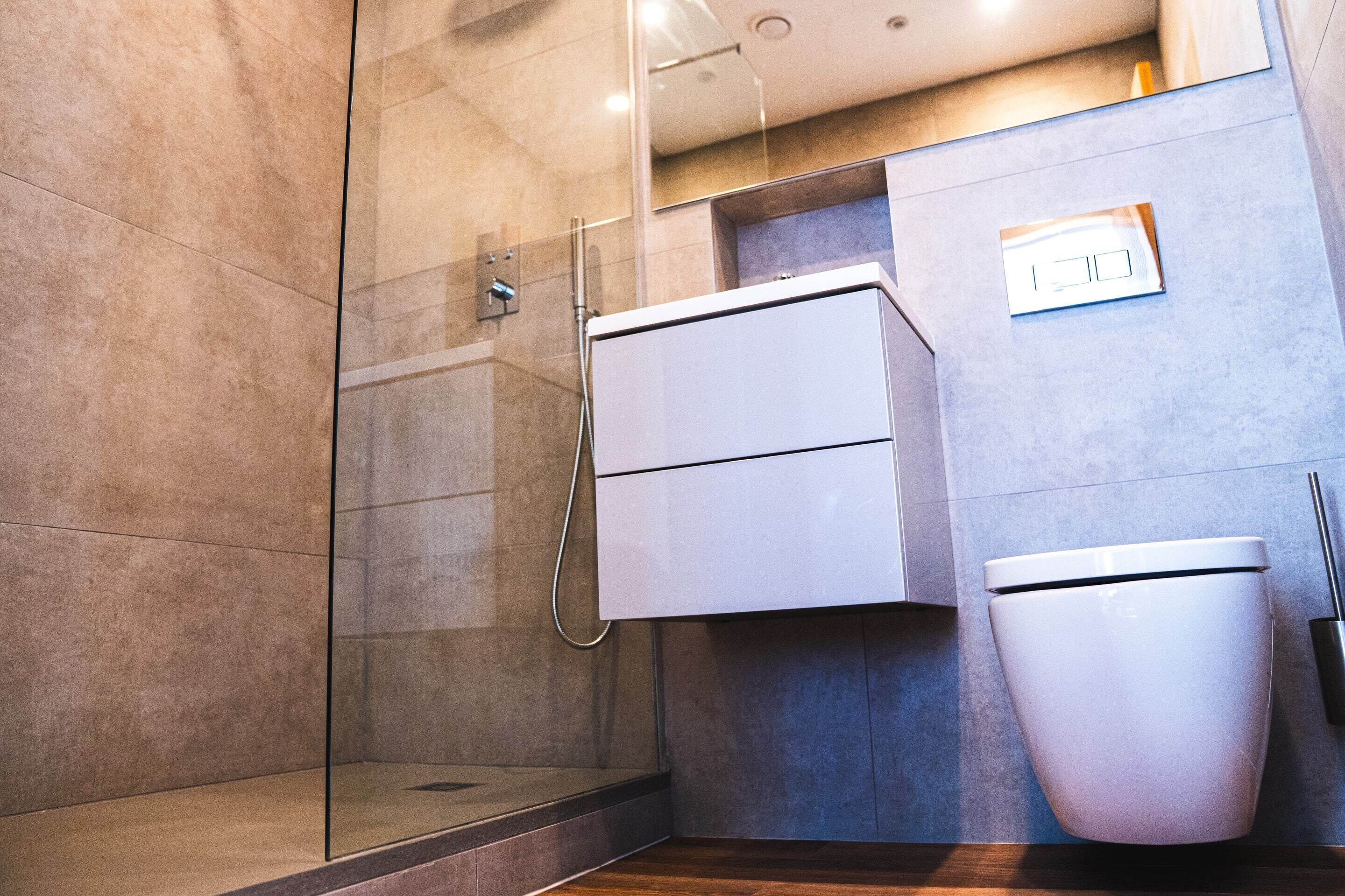 Un baño moderno con cabina de ducha de vidrio, inodoro blanco y mueble empotrado.
