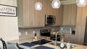 A modern kitchen with wooden cabinets, stainless steel appliances, and a central island with bar stools.