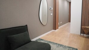 A modern hotel room with a large mirror, a dark green sofa, and a wooden floor. - In the heart of Aveiro! Cozy accommodation in Portuguese Venice (Aveiro)