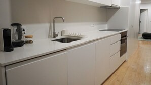A modern kitchen with white cabinetry, a stainless steel sink, and a built-in oven. - In the heart of Aveiro! Cozy accommodation in Portuguese Venice (Aveiro)