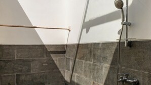 A modern shower area with a glass ceiling, stone walls, and a metal showerhead. - omaneil (Pecatu)