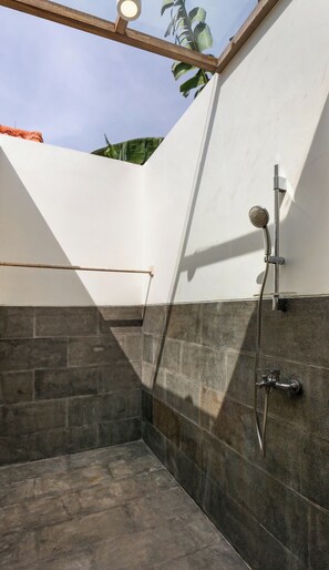 A modern shower area with a glass ceiling, stone walls, and a metal showerhead. - omaneil (Pecatu)