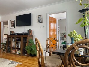 A dining area with a wooden table, chairs, and a television mounted on the wall. - Cozy Vintage Music House In the Heart of London (London)