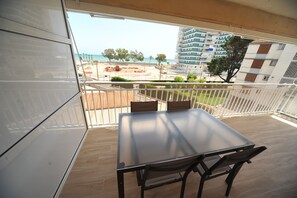 A balcony with a table and chairs, overlooking a beach and buildings. - ESTORIL BLOCK 3 PREMIUM (Benicàssim)