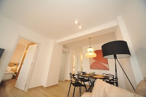 Un salon moderne comprenant un coin repas, un canapé, une lampe et un tableau accroché au mur.