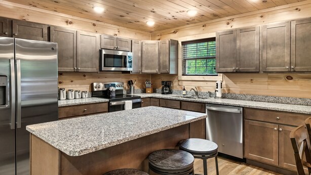 A modern kitchen with granite countertops, stainless steel appliances, and wooden cabinetry. - Tranquil Haven - Modern Cabin Retreat - Book Your Spring Break Now (Sevierville)