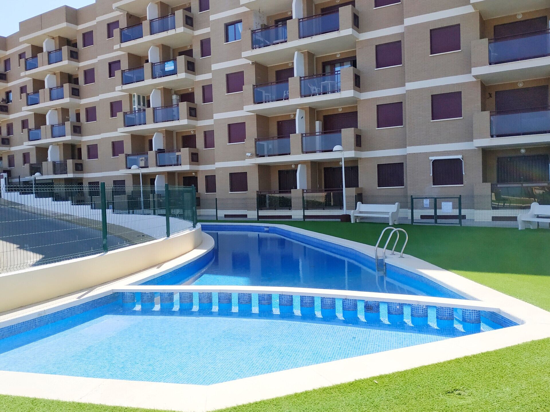 Un immeuble d’appartements moderne doté d’une piscine et d’une pelouse verdoyante.