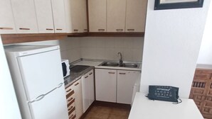 A compact kitchen with white cabinets, a white refrigerator, a microwave, and a sink. - EL PARAISO OCEAN VIEW (Peñiscola)