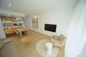 A modern living room with a dining area, a sofa, a TV, and a kitchen in the background. - PRINCICASIM (Benicàssim)