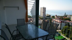A balcony with a glass table and chairs, overlooking a cityscape and the sea. - PRINCICASIM (Benicàssim)