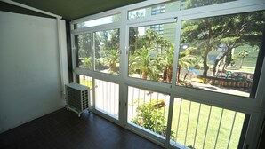 A room with large windows, a radiator, and a view of a park with trees and a playground. - PRINCICASIM (Benicàssim)