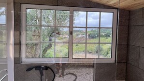 Un baño con un ventanal grande, paredes de piedra y techo de madera.