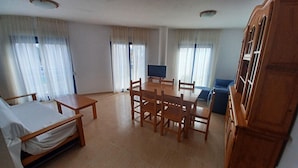 Amplia sala de estar con una mesa de comedor de madera, sillas, un sofá y un televisor.